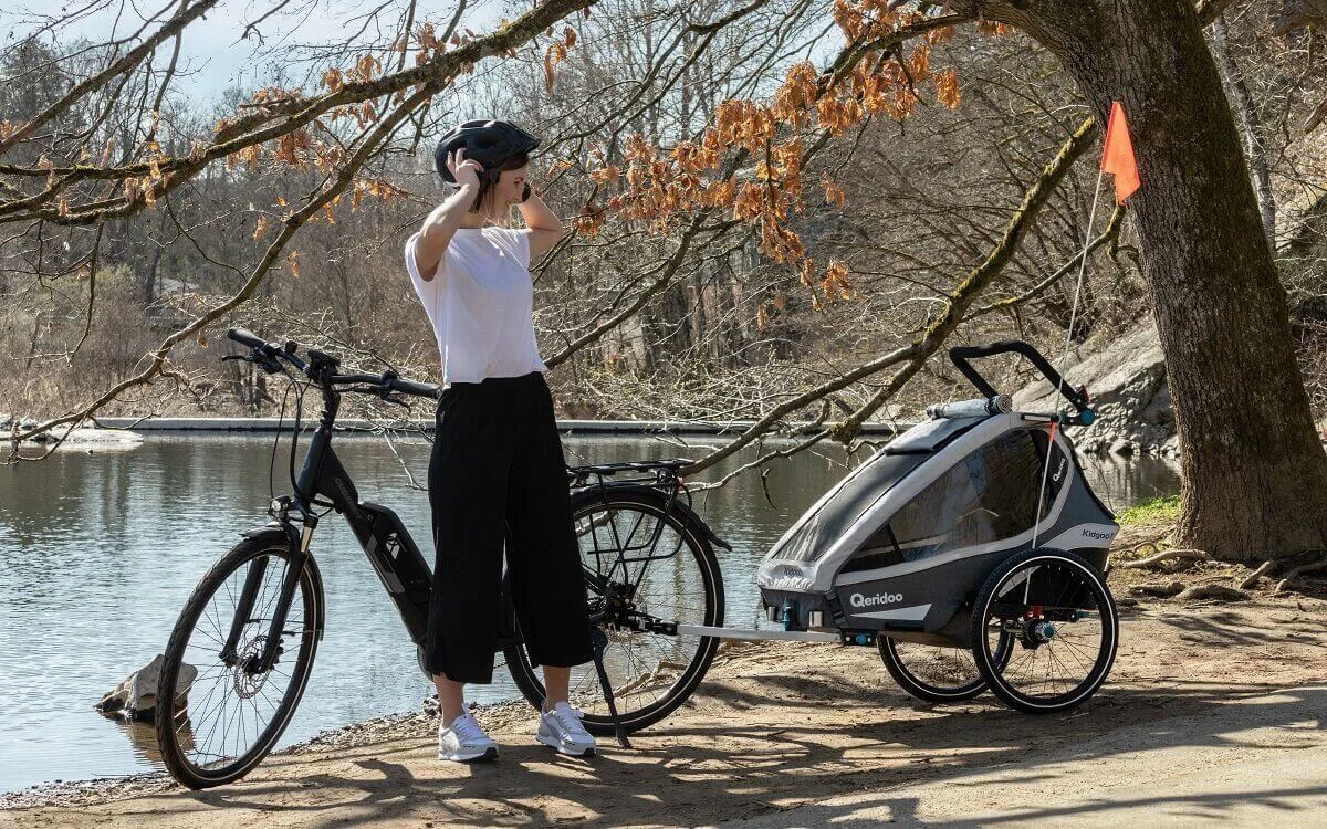 Bild Frau neben E-Bike und Qeridoo Kinderfahrradanhänger
